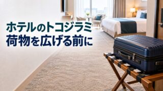 ベッドから離した荷物台に、閉じたスーツケースを置いたホテル客室のイメージ